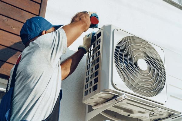 Technician installing an air conditioning unit in a home.